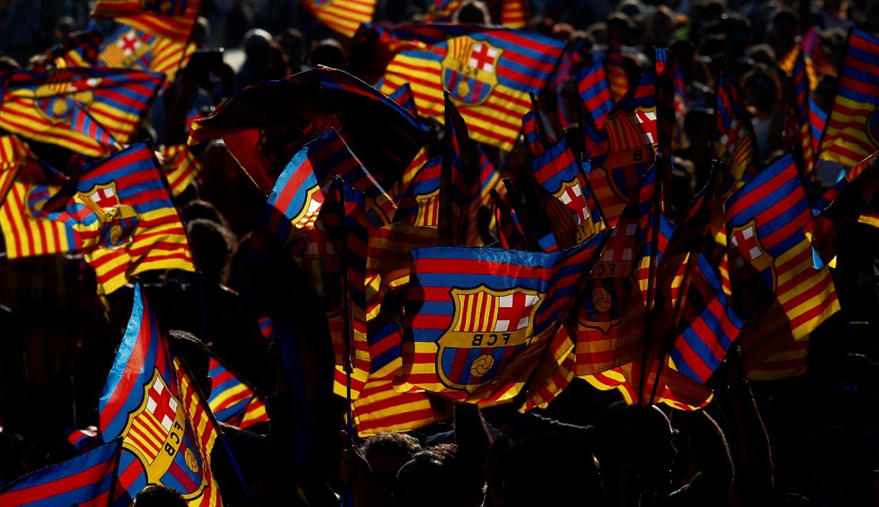 Siluet suporter yang mengibarkan bendera Barcelona saat pawai menyambut gelar La Liga ke-24, Minggu (15/5/2016). (AFP/Pau Barrena)