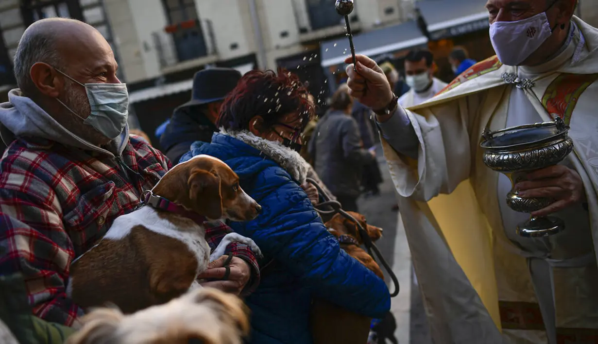 Pendeta Cesar Magana (tengah) memberkati hewan dan pemiliknya saat pesta Santo Antonius di Pamplona, Spanyol, 17 Januari 2022. Pesta santo pelindung hewan Spanyol ini dirayakan setiap tahun dan orang-orang membawa hewan peliharaan mereka ke gereja untuk diberkati. (AP Photo/Alvaro Barrientos)