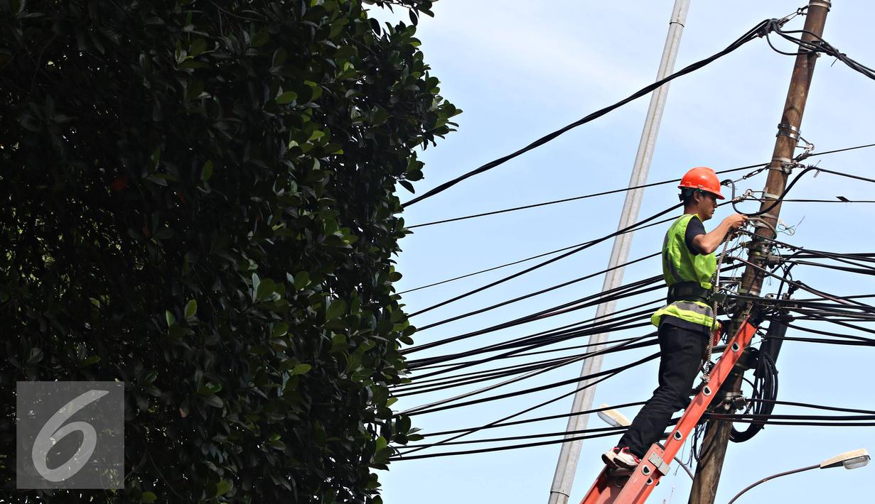 Pekerja mengecek instalasi kabel di tiang listrik milik PLN, Jakarta, Jumat (26/2). PLN menjaga mutu keandalan penyaluran tenaga listrik, memenuhi ketentuan keselamatan ketenagalistrikan, dan estetika tata kota Jakarta. (Liputan6.com/Immanuel Antonius)