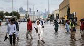 Orang-orang menerobos genangan air banjir setelah hujan lebat di Dubai, Uni Emirat Arab (UEA) pada Jumat 19 Desember 2025. Hujan lebat yang terjadi pada Jumat 19 Desember 2025 berimbas pada genangan banjir di sejumlah ruas jalan di Dubai, Uni Emirat Arab (UEA). (FADEL SENNA/AFP)
