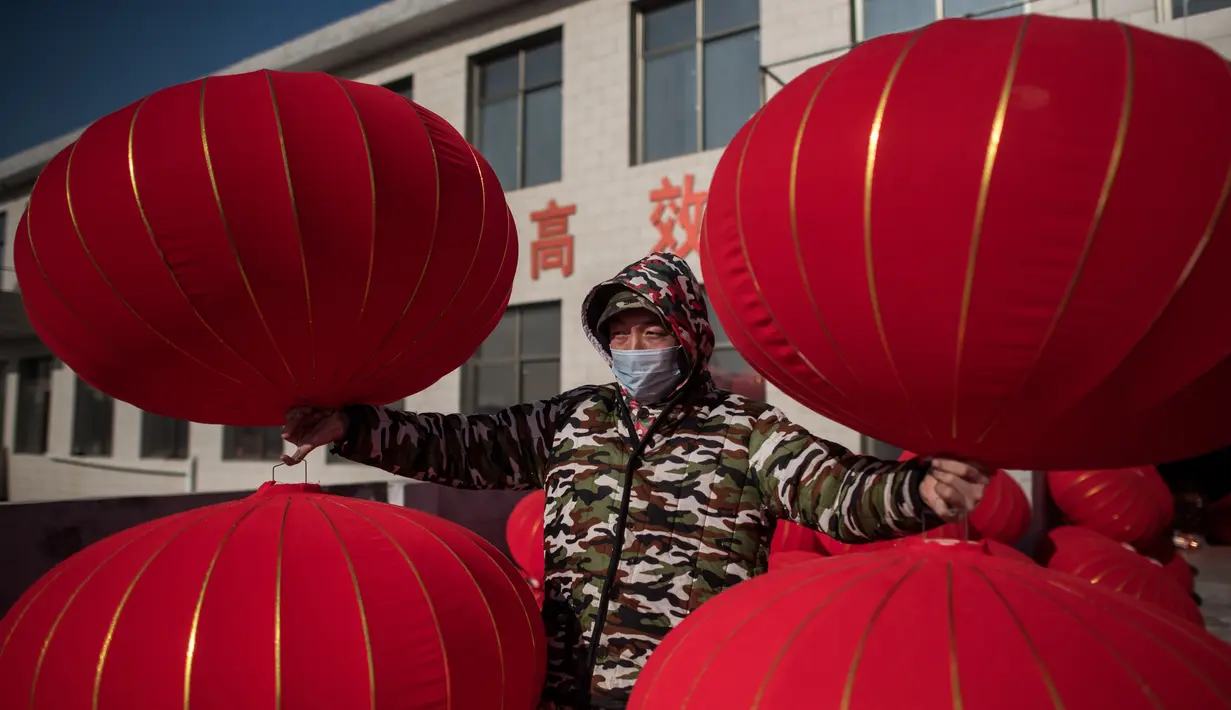 Pekerja membawa lampion yang sudah jadi untuk dijemur jelang perayaan Tahun Baru Imlek di provinsi Hebei, Tingkok (11/1). (AFP Photo/Fred Dufour)