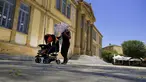 Seorang perempuan melindungi dirinya dari sinar matahari dengan payung sambil mendorong bayinya di kereta dorong pada siang hari yang terik di alun-alun Phaneromeni di pusat ibu kota Nicosia, Siprus, Selasa (4/6/2024). (AP Photo/Petros Karadjias)