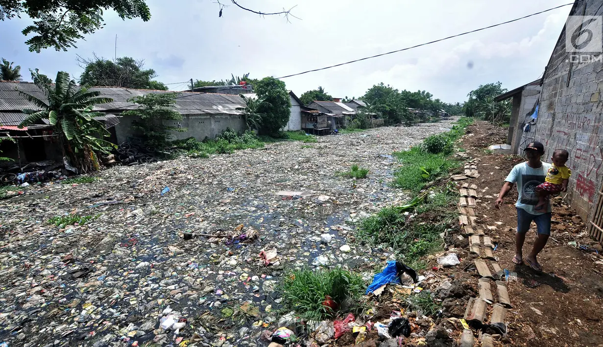 Warga melintas di pinggir Kali Pisang Batu yang dipenuhi sampah, Tarumajaya, Bekasi, Rabu (9/1). Tumpukan sampah tersebut berasal dari limbah rumah tangga. (Merdeka.com/Iqbal S Nugroho)