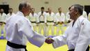 Presiden Rusia, Vladimir Putin menyapa pelatih sebelum mengikuti latihan judo bersama atlet nasional Rusia di Sochi, Kamis (14/2). Judo merupakan salah satu olahraga kegemaran Putin yang telah digeluti sejak masa muda. (Mikhail KLIMENTYEV/SPUTNIK/AFP)