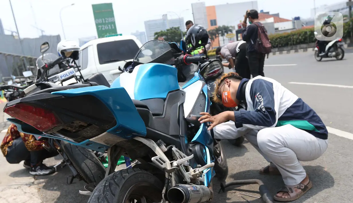 Pengendara motor mencopot knalpot bising usai terjaring razia yang digelar Satlantas Polres Metro Depok di Jalan Margonda Raya, Depok, Kamis (18/3/2021). Puluhan motor berknalpot bising yang terjaring razia diwajibkan mengganti knalpot dan diberi sanksi tilang. (Liputan6.com/Helmi Fithriansyah)