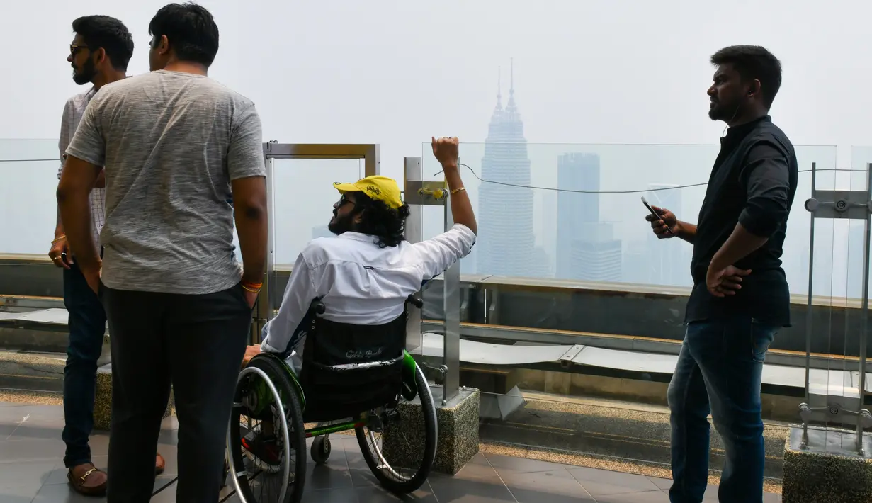 Wisatawan melihat cakrawala Kuala Lumpur, termasuk Menara Kembar Petronas, yang diselimuti kabut asap di Kuala Lumpur (11/9/2019). Kualitas udara turun ke tingkat "tidak sehat" di  sekitar Kuala Lumpur, menurut indeks polusi udara pemerintah. (AFP Photo/Mohd Rasfan)