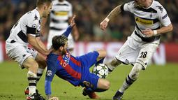 Bintang Barcelona, Lionel Messi, terjatuh saat berebut bola dengan pemain Gladbach. Kemenangan ini semakin mengukuhkan Barcelona di puncak klasemen Grup C dengan nilai 15. (AFP/Lluis Gene)