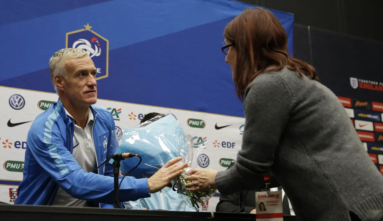 Pelatih Prancis, Didier Deschamps menerima bunga dari seorang jurnalis sebagai tanda berduka cita saat jumpa pers di Inggris, Senin (16/11/2015). (Action Images via Reuters/Henry Browne)