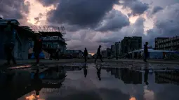 Diperkirakan, sekitar 70 persen lebih bangunan hancur atau rusak parah. Tampak dalam foto, orang-orang berjalan melewati genangan air di lingkungan Al-Saftawi, sebelah barat kota Jabalia di Jalur Gaza utara pada Rabu 10 Desember 2025. (BASHAR TALEB/AFP)
