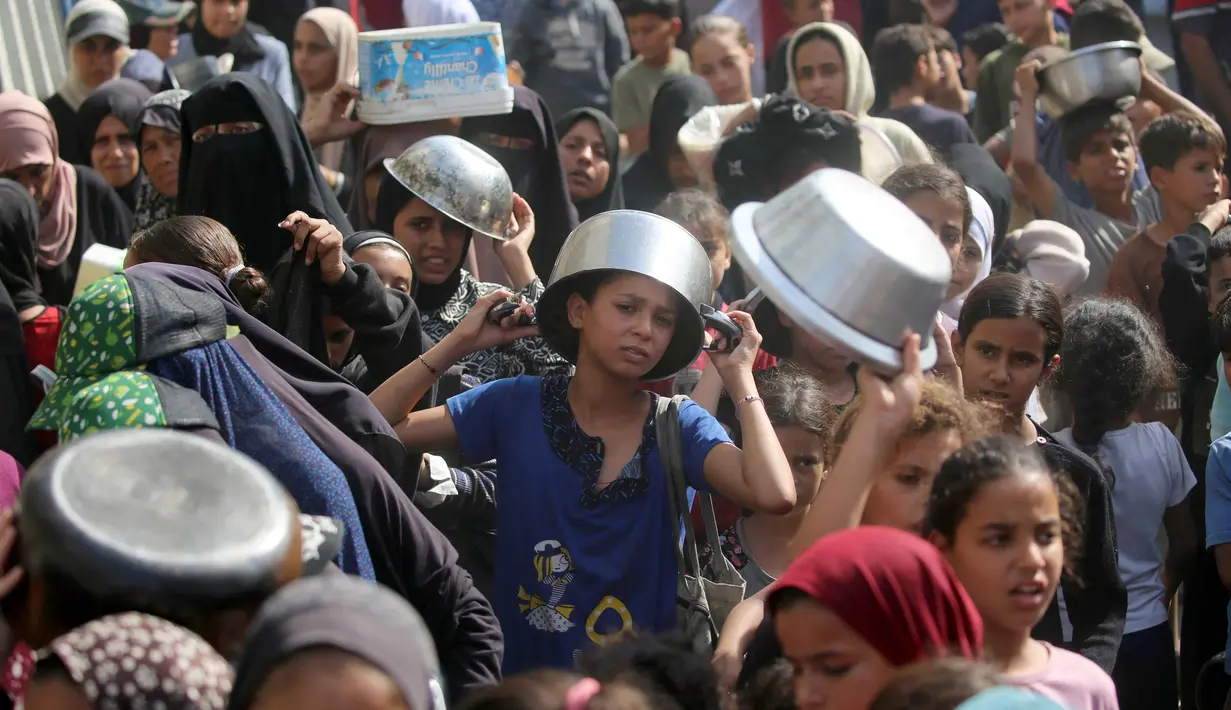 Seorang anak laki-laki Palestina yang sedang menunggu dengan pancinya untuk menerima seporsi makanan, di sebuah tempat penampungan yang telah dihuni banyak keluarga, di Nuseirat, pusat Jalur Gaza, pada 2 November 2025. Di sisi lain, PBB terus menyalurkan bantuan kemanusiaan di seluruh Gaza meski wilayah tersebut beberapa kembali diguncang serangan udara Israel. (EYAD BABA/AFP)