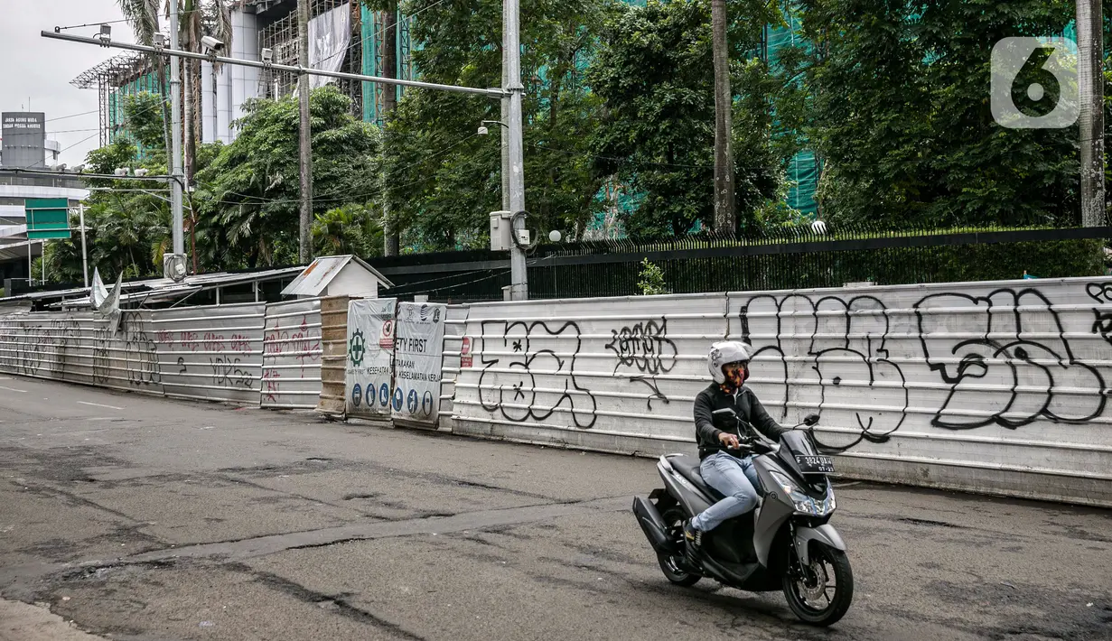 Pengendara sepeda motor melintasi proyek pembangunan jembatan layang atau skybridge untuk integrasi Halte Transjakarta Centrale Stichting Wederopbouw (CSW) di Stasiun MRT Asean, Jakarta, Selasa (19/1/2021). Terlihat banyak coretan pada proyek pembangunan Skybridge CSW. (Liputan6.com/Faizal Fanani)