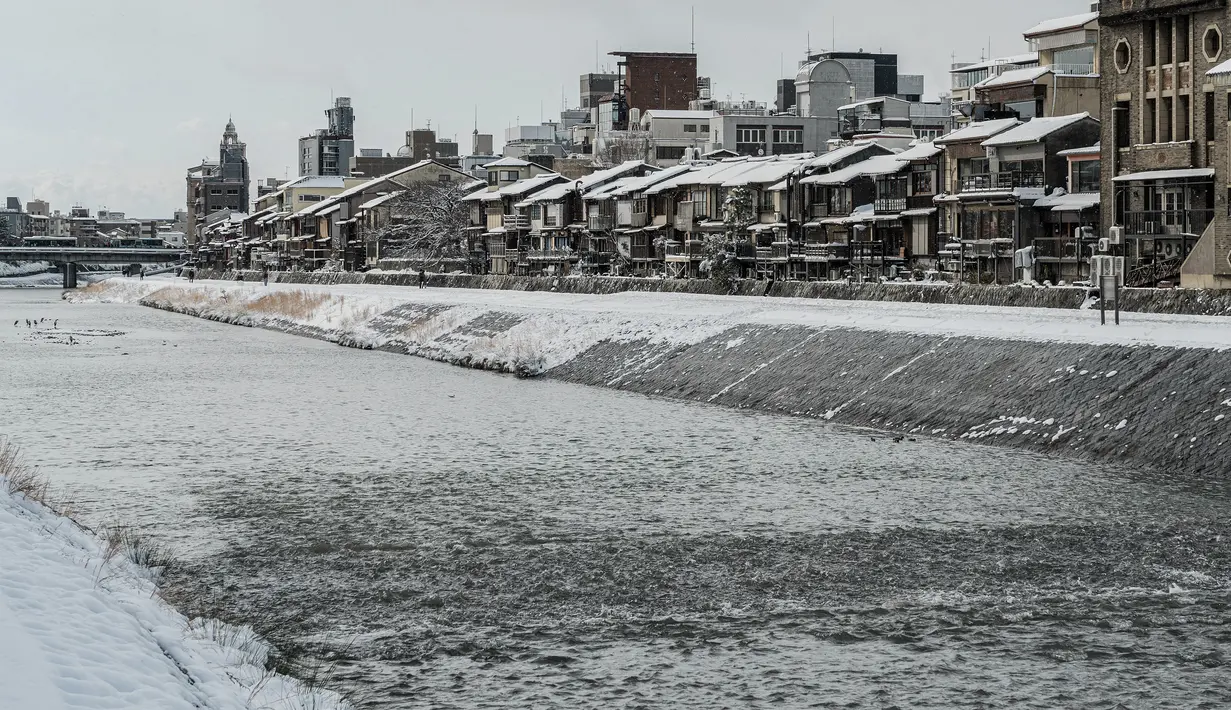 Pandangan umum menunjukkan bangunan yang tertutup salju di sepanjang Sungai Kamo setelah salju tebal dan angin kencang semalaman mempengaruhi wilayah luas negara itu di Kyoto, Jepang, Rabu (25/1/2023). Hal itu karena cuaca bertekanan rendah di dekat Hokkaido dan Jepang selatan akan membawa udara terdingin pada musim dingin ini dan membuat kondisi atmosfer menjadi sangat tidak stabil, kata Badan Meteorologi Jepang. (Fred Mery / AFP)