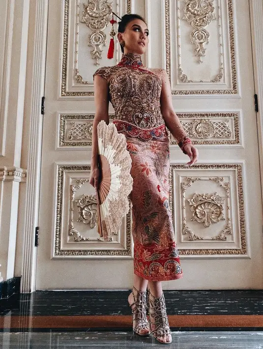 Agnez Mo tampil dengan busana percampuran China dan Indonesia. Dengan atasan kebaya model kerah tinggi dipadukan bawahan kain batik. Ia mengenakan tusuk konde khas China. [@agnezmo]