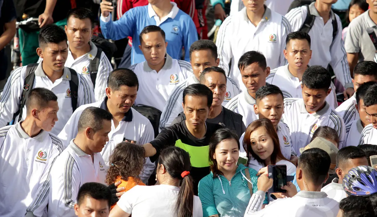 Presiden RI, Joko Widodo bersepeda di Hari Bebas Kendaraan Bermotor di kawasan Bundaran Hotel Indonesia, Minggu (11/1/2015). Tampak, Presiden Jokowi menyapa salah satu anak yang berada dalam gendongan. (Liputan6.com/Faizal Fanani)