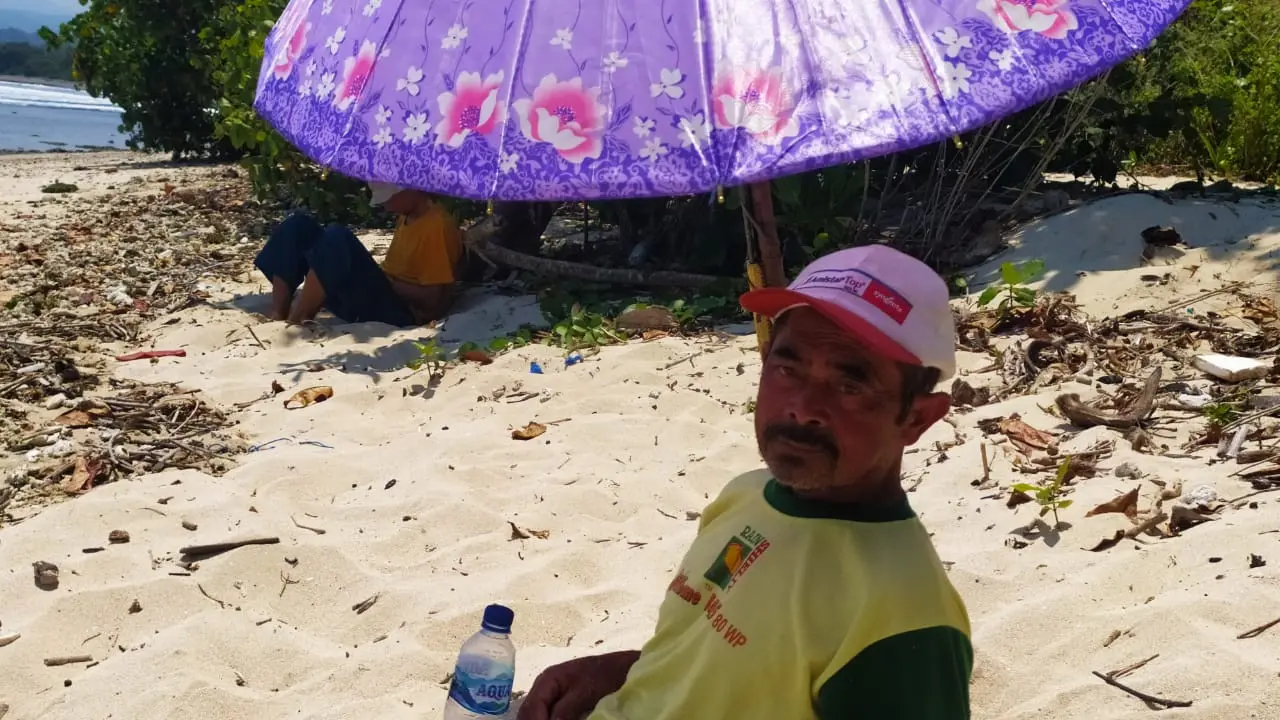 Aef, salah seorang pasien sakit otot dan persendian, tengah menikmati sensasi terapi pasir laut di Pantai Cijeruk, Cibalong, Garut, Jawa Barat.