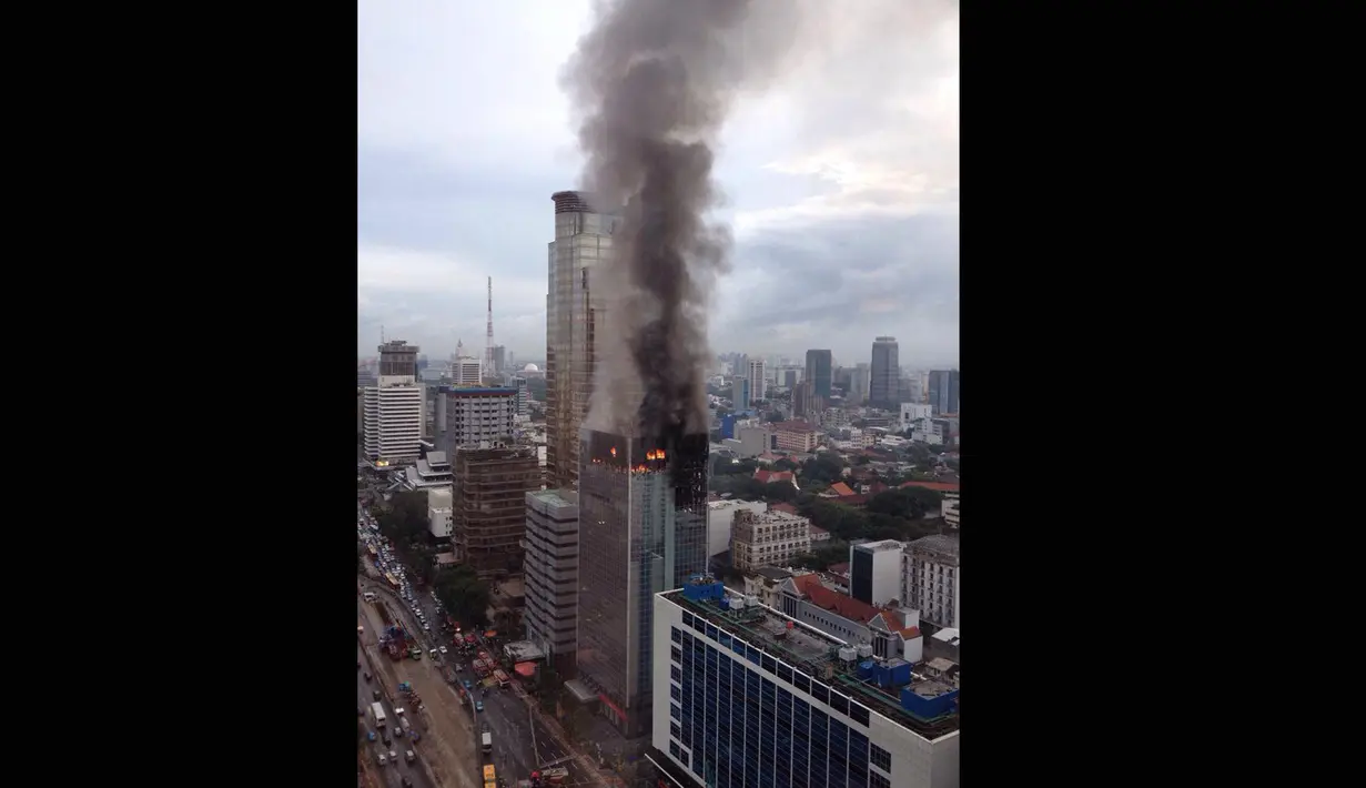 Api disertai asap pekat masih membubung di atas Gedung Wisma Kosgoro di Jalan MH Thamrin, Jakarta Pusat hingga pagi ini, Selasa (10/3/2015). (twitter.com/Peddy_Robot)