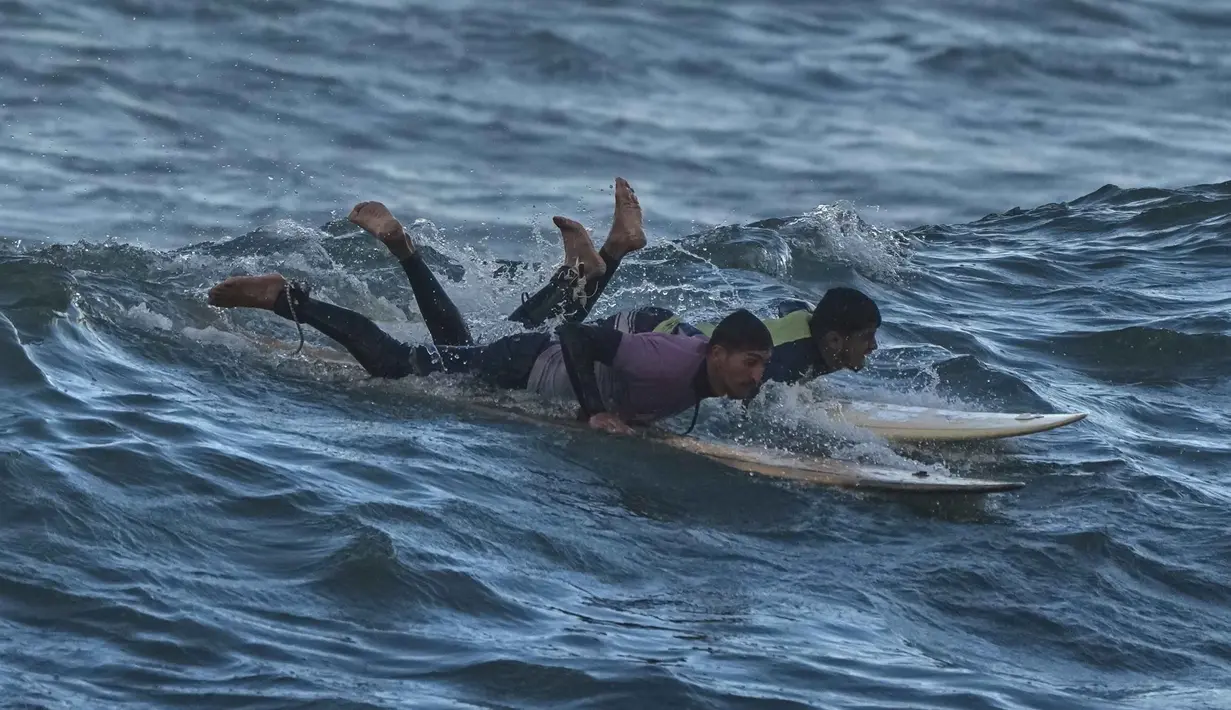 Bagi warga Palestina di Gaza, laut dan berselancar dianggap sebagai simbol kebebasan dan harapan di tengah keterbatasan ruang gerak akibat blokade dan konflik. Tampak dalam foto, warga Palestina, Khalil Abu Jayyab (kanan) dan Tahseen Abu Assi berselancar di pantai Kota Gaza, Minggu, 28 Desember 2025. (AP Photo/Jehad Alshrafi)