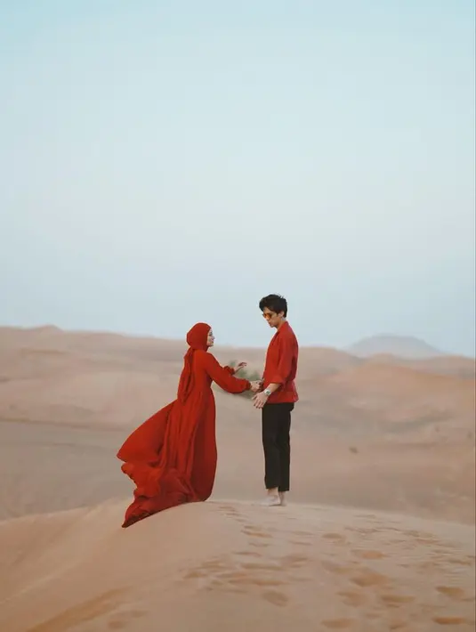 Dinda Hauw dan Rey Mbayang terlihat begitu kompak dengan baju warna merah yang sangat kontras dengan gurun pasir di sekitarnya. (Instagram/dindahw).