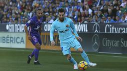 Bintang Barcelona, Lionel Messi, menggiring bola melewati striker Leganes, Nabil El Zhar, pada laga La Liga Spanyol di Stadion Butarque, Leganes, Sabtu (18/11/2017). Leganes kalah 0-3 dari Barcelona. (AP/Francisco Seco)