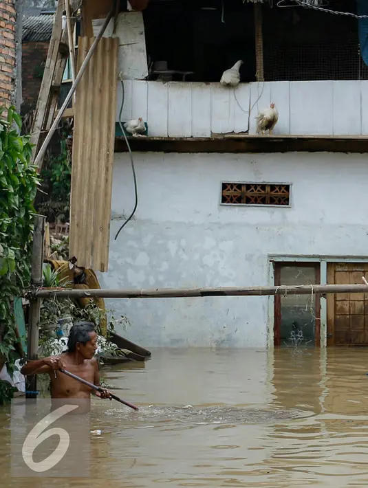 Warga melintasi banjir yang mulai memasuki belasan rumah warga di RT 11/ RW 07 sejak pukul 01.00 WIB dini hari tadi, Jakarta, Senin (16/11/2015). Ratusan warga kini sibuk mengeruk lumpur-lumpur yang memenuhi rumah mereka. (Liputan6.com/Yoppy Renato)