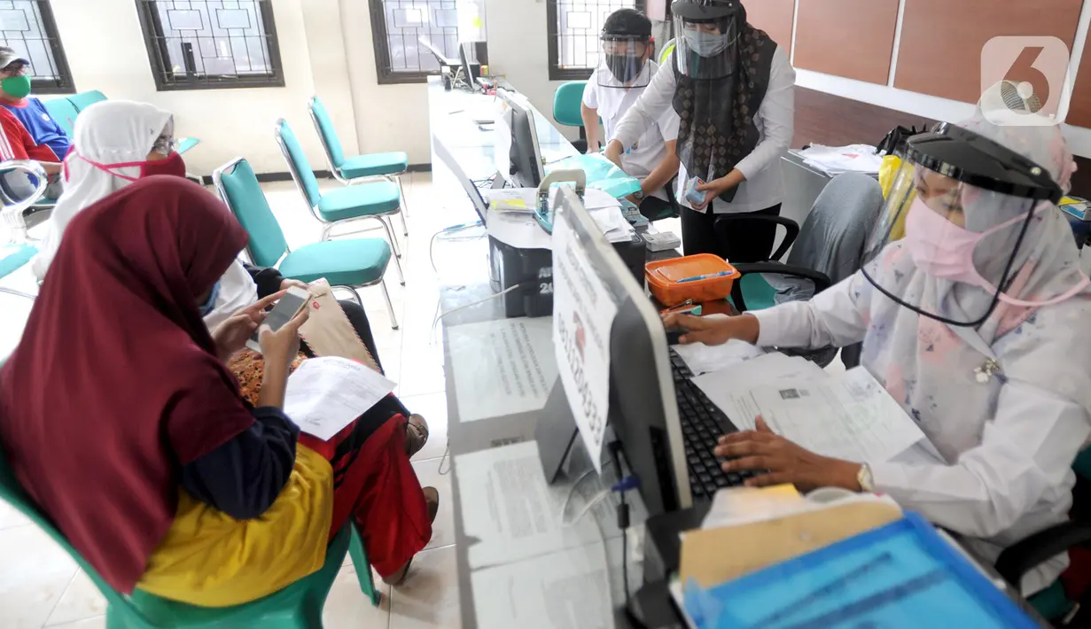 Petugas Dinas Kependudukan dan Catatan Sipil menggunakan pelindung wajah saat melayani warga di Kecamatan Pamulang, Tangerang Selatan, Rabu (3/6/2020). Sejumlah kantor pelayanan pemerintah melaksanakan protokol kesehatan yang ketat untuk memutus rantai penyebaran covid-19. (merdeka.com/Arie Basuki)