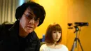 Insinyur robot Jepang Hiroshi Ishiguro berpose di sebelah robotnya yang bernama Erica selama presentasinya di Konferensi Internasional IROS 2018 di Madrid, Spanyol (5/10). (AFP Photo/Gabriel Bouys)