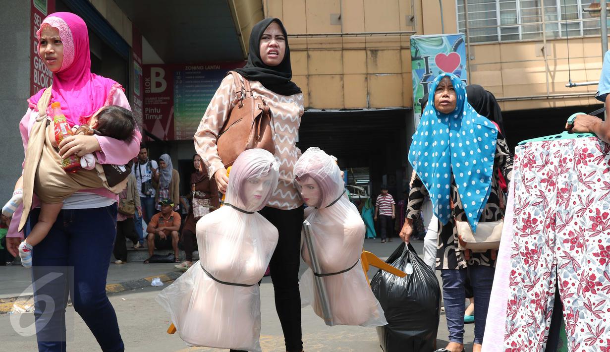 Sejumlah pembeli membawa barang belanjaan mereka di Pasar Tanah Abang, Jakarta, Rabu (9/12). Libur pilkada dimanfaatkan warga untuk berbelanja pakaian di pasar tekstil terbesar di Asia Tenggara itu. (Liputan6.com/Angga Yuniar)