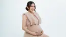 Pakai gaun sleeveless warna cokelat berbahan tile, Vicy Melanie tampil anggun dan terlihat seperti putri. Rambut yang disanggul dengan juntaian poni di samping kiri dan kanannya, aura Vicy Melanie kian terpancar di pemotretan maternity shootnya ini. Wajah cantik artis berusia 35 tahun ini dipoles oleh MUA Annesya. Tonjolkan highlighter blush, Vicy Melanie memukau. (Liputan6.com/IG/@vicymelanie)