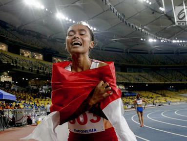 Pelari Indonesia Triyaningsih membawa bendera merah putih setelah mencapai garis finis dalam cabang olahraga atletik nomor lari 10 km putri SEA Games 2017 di Stadion Nasional Bukit Jalil, Malaysia, Kamis (24/8). (Liputan6.com/Faizal Fanani)