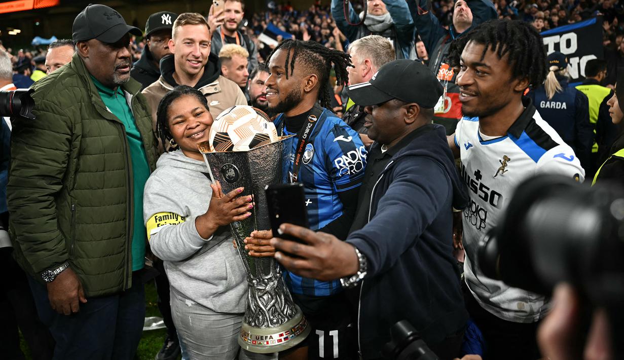 Pemain Atalanta, Ademola Lookman (tengah) merayakan gelar juara Liga Europa 2023/2024 bersama keluarganya setelah laga final melawan Bayer Leverkusen di Dublin Arena, Irlandia, Kamis (23/05/2024) dini hari WIB. (AFP/Paul Ellis)