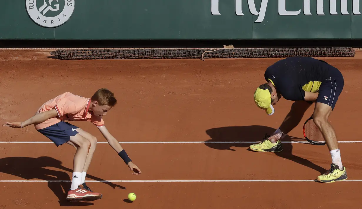 Seorang ball boy mengambil bola saat petenis Serbia, Dusan Lajovic gagal mengembalikan bola ke arah petenis Jerman, Alexander Zverev pada ajang Prancis Terbuka 2018 di Roland Garros stadium, Paris, France, (30/5/2018). (AP/Alessandra Tarantino)
