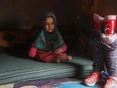 Bocah Suriah, Maya Merhi berpose dekat kaki prostetiknya yang dihiasi bendera Turki di kamp Serjilla, 9 Desember 2018. Sebelumnya, gadis 8 tahun yang lahir tanpa kaki karena kondisi bawaan terpaksa menggunakan kaki palsu dari kaleng. (Aaref WATAD/AFP)