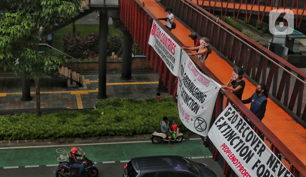 Sejumlah aktivis yang tergabung dalam Extintion Rebellion (XR) dan Walhi Jakarta melakukan aksi di JPO Pinisi, Jalan Jenderal Sudirman, Jakarta, Senin (14/11/2022). Aksi tersebut dilakukan untuk menyerukan kepada para pemimpin agar menghentikan “pencucian hijau” dan praktik ekonomi “business-as-usual” yang secara sistematis memperburuk krisis iklim dan mendorong umat manusia pada kehancuran ekologis & kepunahan massal. Negara-negara G20 turut menyumbang atas 80 persen emisi karbon dunia dan 60 persen populasi penduduk bumi. (Liputan6.com/Angga Yuniar)