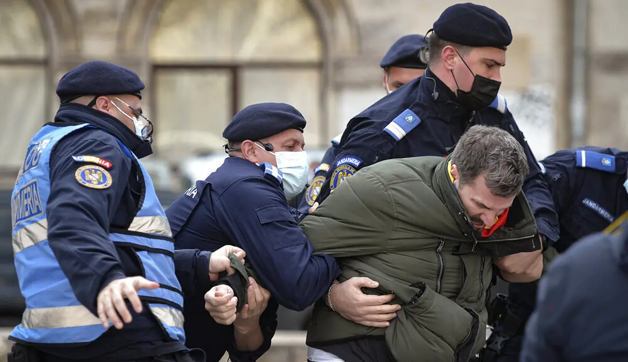 Polisi antihuru-hara menahan seorang pengunjuk rasa terkait pembatasan COVID-19 di Bucharest, Rumania, Senin (29/3/2021). Ribuan pengunjuk rasa antipembatasan turun ke jalan sehari setelah langkah pembatasan baru diberlakukan. (AP Photo/Vadim Ghirda)