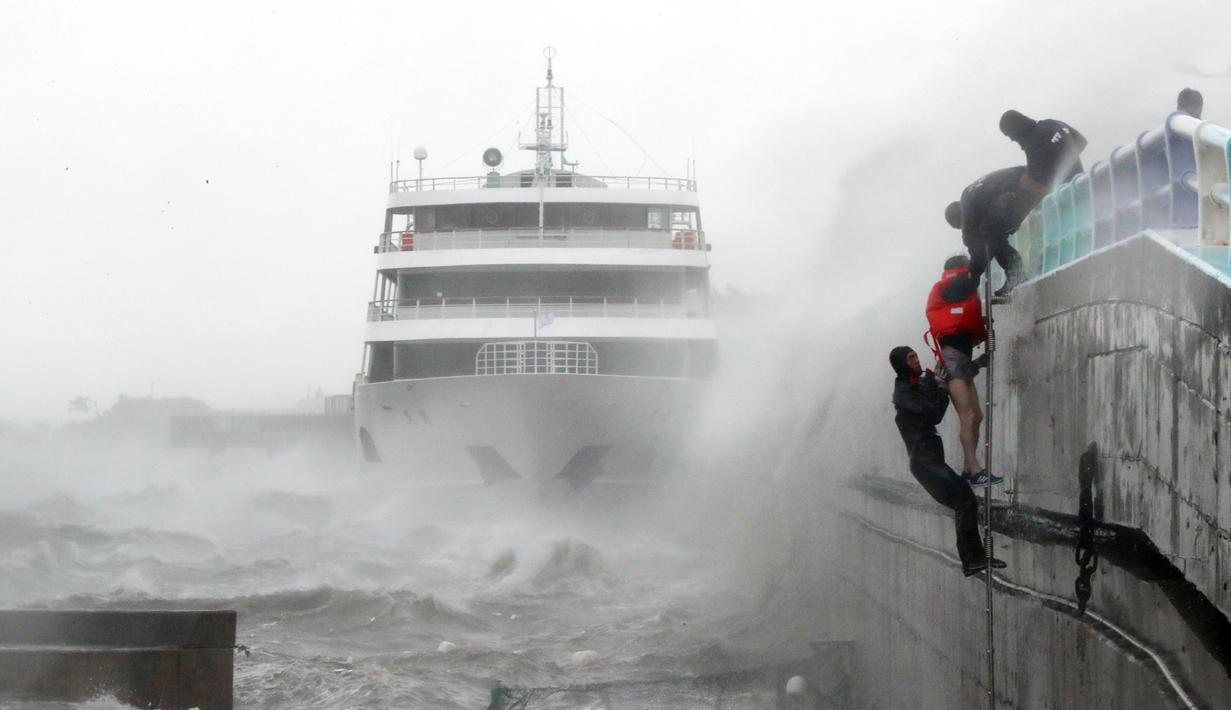 Seorang anggota kru (memakai jaket merah) dari kapal penumpang yang terdampar karena topan Chaba diselamatkan oleh petugas polisi maritim di Yeosu, Korea Selatan, 5 Oktober 2016. (REUTERS/Kim Yong-tae / Yonhap)