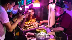 Seorang pedagang menyajikan hidangan lokal kepada para pelanggan di sebuah pasar malam di Hotan, Daerah Otonom Uighur Xinjiang, China barat laut, pada 18 Mei 2020. Seiring cuaca mulai menghangat, aktivitas pariwisata lokal pun perlahan kembali pulih. (Xinhua/Wang Fei)