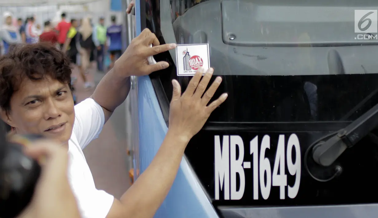 Peserta menempelkan stiker pesan antihoax pada  kampanye sekaligus deklarasi saat car free day di Bundaran Hotel Indonesia, Jakarta, Minggu (18/3). Kegiatan digelar Polda Metro Jaya bersama Indonesia Comunitas Club. (Liputan6.com/Faizal Fanani)