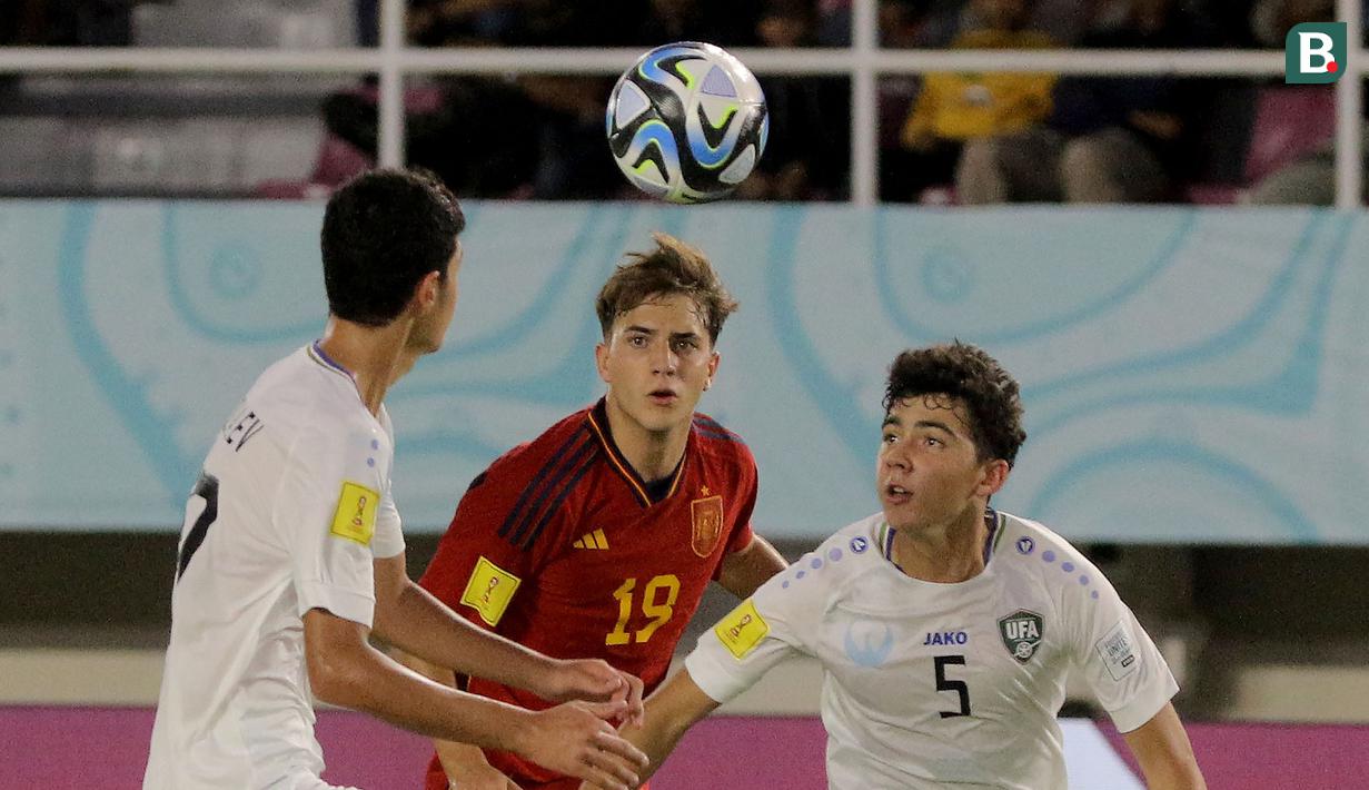 Pemain Timnas Uzbekistan U-17, Azizbek Tulkunbekov (kanan) berusaha meraih bola di udara dari jangkauan pemain Timnas Spanyol U-17, Daniel Yanez (tengah), dalam laga pamungkas Grup B Piala Dunia U-17 2023 yang berlangsung di Stadion Manahan, Solo, Kamis (16/11/2023) sore WIB. (Bola.com/Arief Bagus Prasetiyo)
