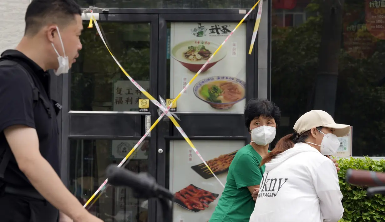 <p>Wanita yang mengenakan masker mengobrol dekat restoran yang ditutup di Beijing, China, 15 Juni 2022. Otoritas China di Beijing menutup distrik perbelanjaan dan kehidupan malam utama menyusul lonjakan kasus COVID-19 terkait klub malam. (AP Photo/Ng Han Guan)</p>