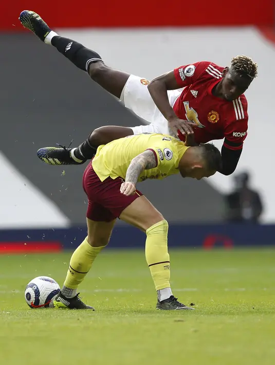 Pemain Manchester United Paul Pogba (atas) berebut bola dengan pemain Burnley Josh Brownhill pada pertandingan Liga Inggris di Stadion Old Trafford, Manchester, Inggris, Minggu (18/4/2021). Manchester United menang 3-1. (Martin Rickett/Pool via AP)