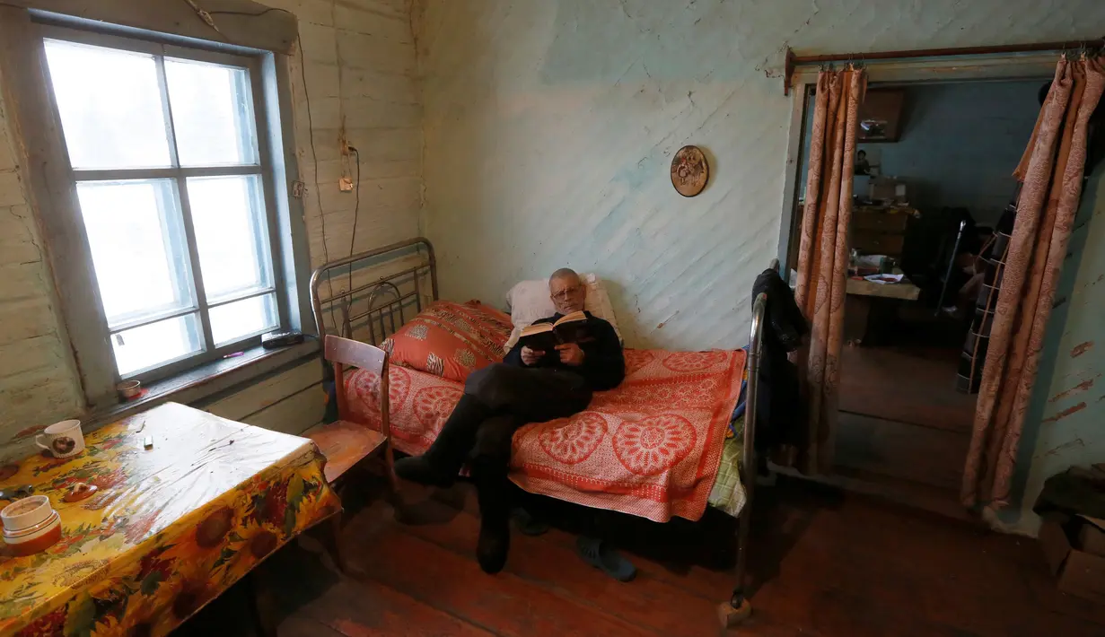 Mikhail Baburin (66) membaca buku sambil bersantai di rumahnya di desa Mikhailovka, Siberia, 5 Desember 2016. Baburin sangat menikmati hari tuanya di desa terpencil Mikhailovka, Siberia, tempat ia dilahirkan. (REUTERS/Ilya Naymushin)