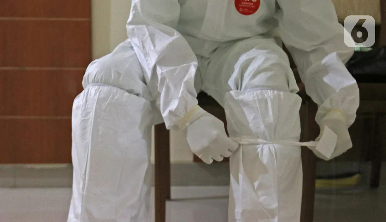 dr Rahmadi Iwan Guntoro, Sp.P membungkus sepatu bootsnya dengan hazmat di Rumah Sakit Haji, Jakarta, Kamis (9/4/2020). Tenaga medis yang menggunakan alat pelindung diri pada tingkatan perlindungan ketiga, yaitu dokter, perawat, dan petugas laboran (laboratorium). (Liputan6.com/Herman Zakharia)