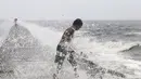 Seorang anak laki-laki mencari botol-botol plastik untuk didaur ulang ditengah deburan gelombang akibat Topan Koppu di Teluk Manila, Minggu (18/10). Topan Koppu melanda Filipina timur laut dan merusak rumah-rumah. (REUTERS/Romeo Ranoco)