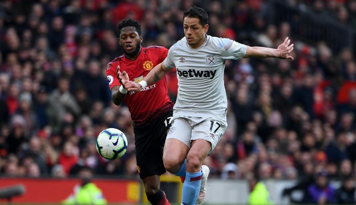 Duel antara Javier Chicharito dan Fred pada laga lanjutan Premier League yang berlangsung di Stadion Old Trafford, Minggu (14/4). Man United menang 2-1 atas West Ham. (AFP/Paul Ellis)