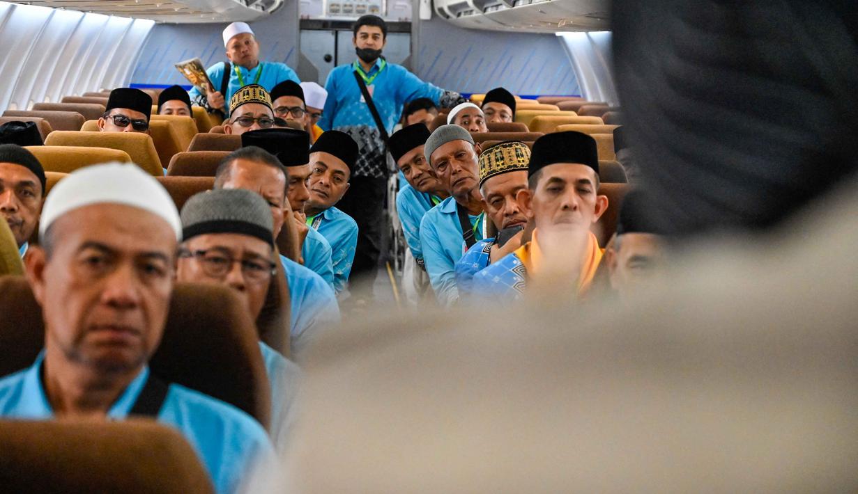 Para calon jemaah haji Indonesia memperhatikan cara menggunakan jaket penyelamat dari awak kabin di dalam pesawat Boeing 717 yang sudah tidak digunakan lagi selama sesi pelatihan keselamatan pra-keberangkatan di pusat embarkasi haji Banda Aceh pada Kamis 14 Mei 2026. (CHAIDEER MAHYUDDIN/AFP)
