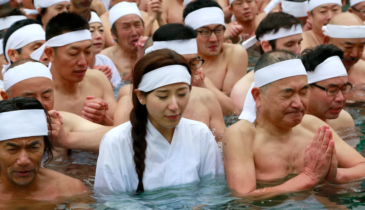 Peserta wanita diantara peserta lainnya ikut berendam di kolam air dingin di Teppozu Inari Shinto Shrine,Tokyo, Jepang (8/1). Tradisi ini diyakini dapat menjaga kesehatan tubuh dan pikiran mereka. (AP Photo/Shizuo Kambayashi)