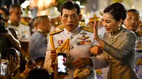 Raja Thailand Maha Vajiralongkorn dan Ratu Suthida menyapa pendukungnya di luar Grand Palace di Bangkok setelah memimpin upacara keagamaan di sebuah kuil Buddha di dalam Istana Raja pada Minggu (1/11/2020). (Lillian SUWANRUMPHA / AFP)