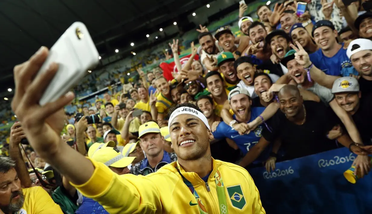 Bintang sepak bola Brasil, Neymar, berfoto bersama pendukungnya setelah meraih emas sepak bola Olimpiade Rio 2016 setelah mengalahkan Jerman di final, (20/8/2016). (AFP/Odd Andersen)