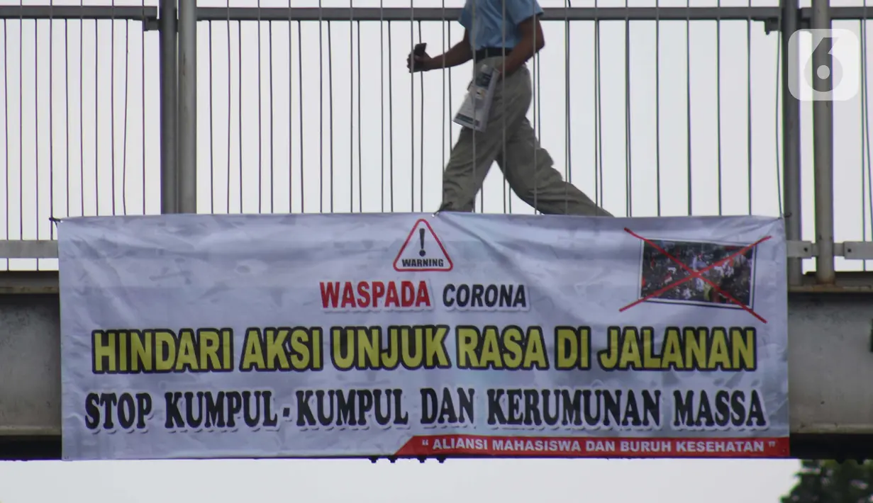 Pejalan kaki melintasi Jembatan Penyeberangan Orang (JPO) di Jalan Raya Lenteng Agung, Jakarta, Selasa (17/3/2020). Sebuah spanduk berisi ajakan menghindari kerumunan dan kumpul-kumpul untuk mencegah penyebaran virus Corona COVID-19 terpasang di JPO teresebut. (Liputan6.com/Helmi Fithriansyah)