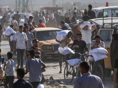 Para pengungsi Palestina mengangkut kantong-kantong bantuan makanan setelah menyerbu gudang Program Pangan Dunia di Deir el-Balah di Jalur Gaza tengah pada 28 Mei 2025. (Eyad BABA/AFP)